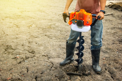 using powered auger to drill holes for planting trees