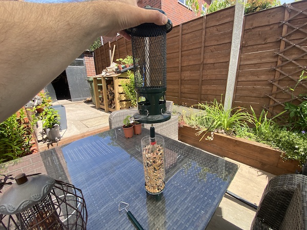 You simply remove the top hanging bar which is just a simple hook and the lift the outside off the tube to refill with seed